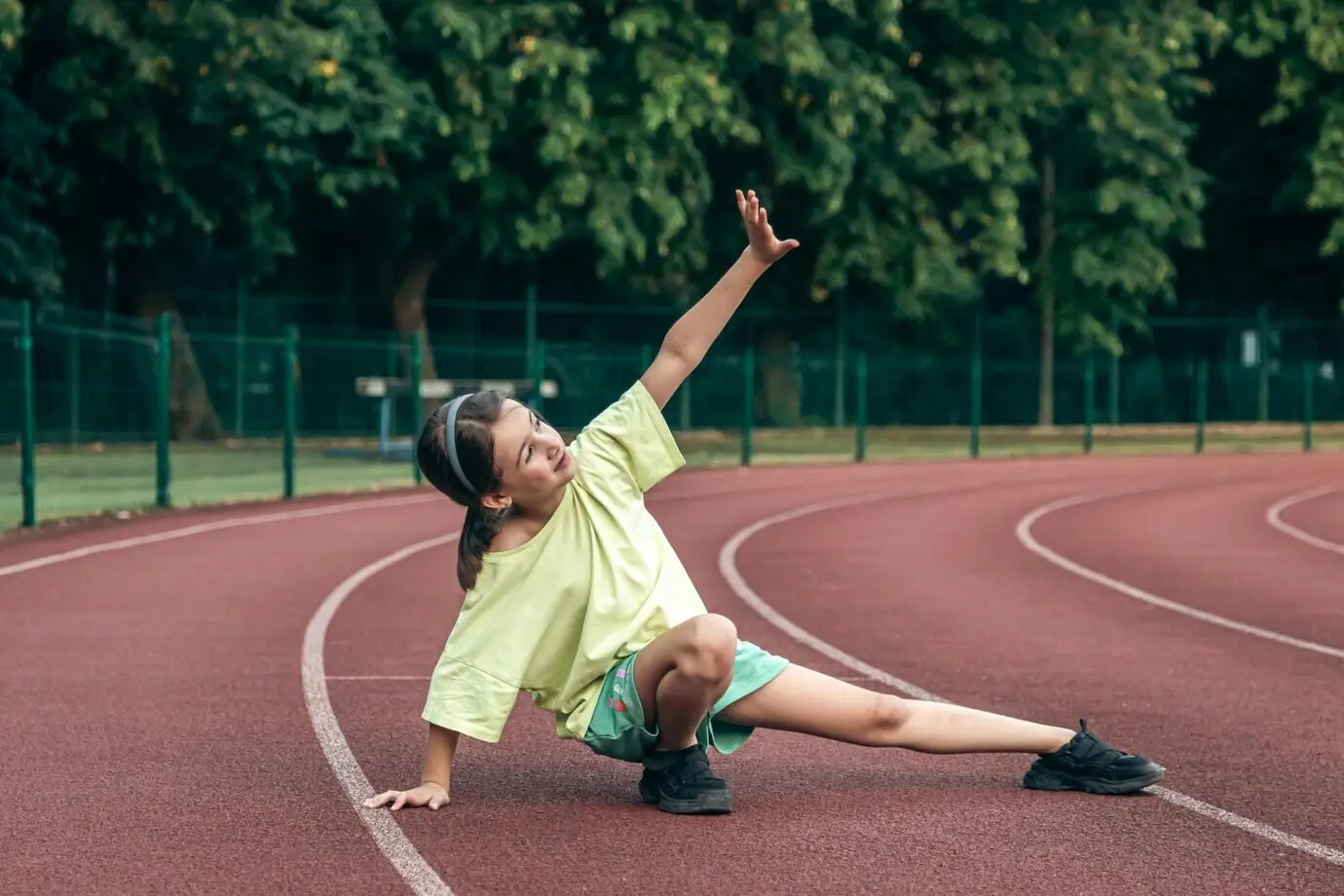 A teenage schoolgirl training outdoors, stretching during a school physical education class.